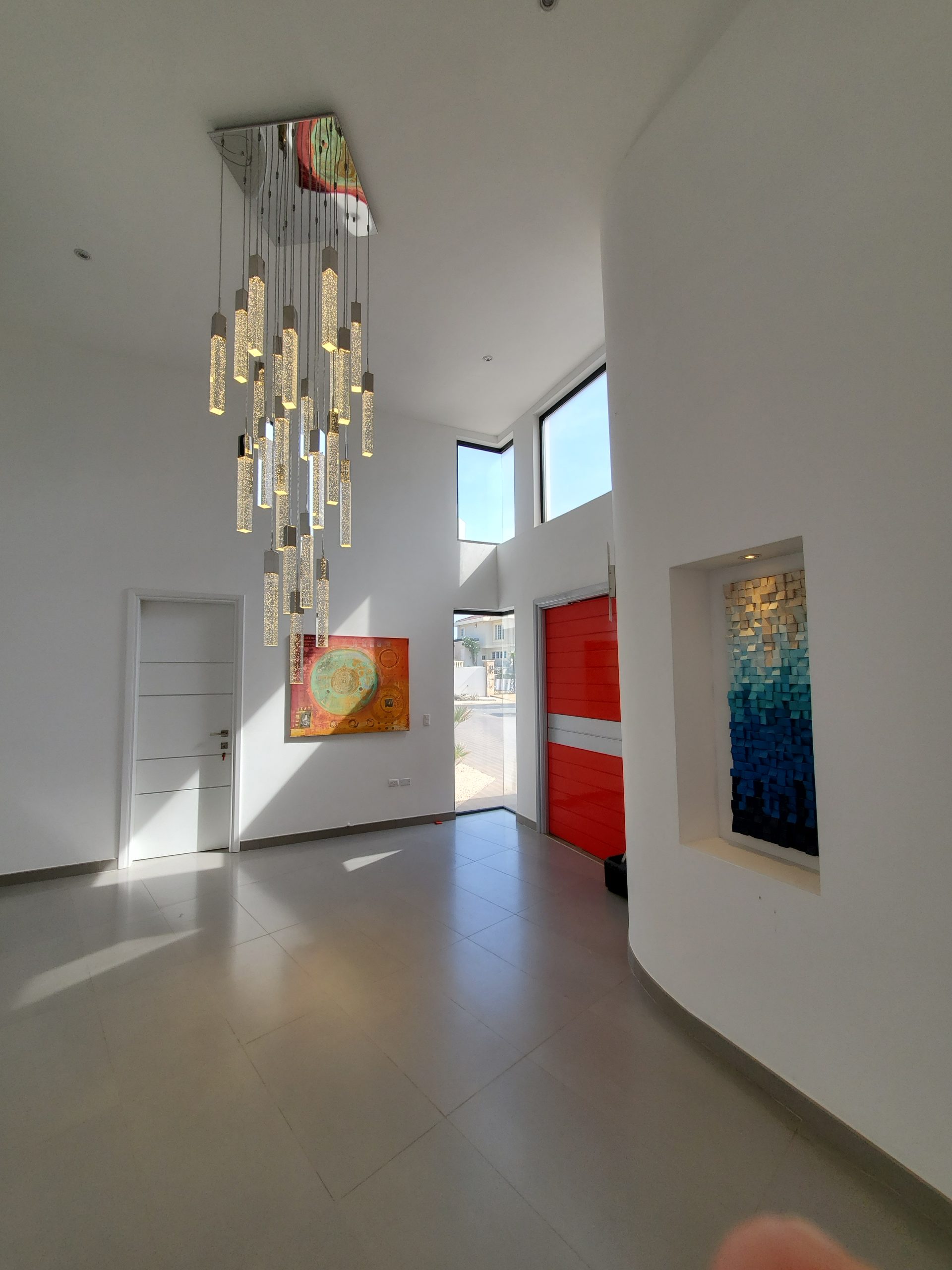 Blue and cream modular relief installed in a recessed wall beside a red front door.