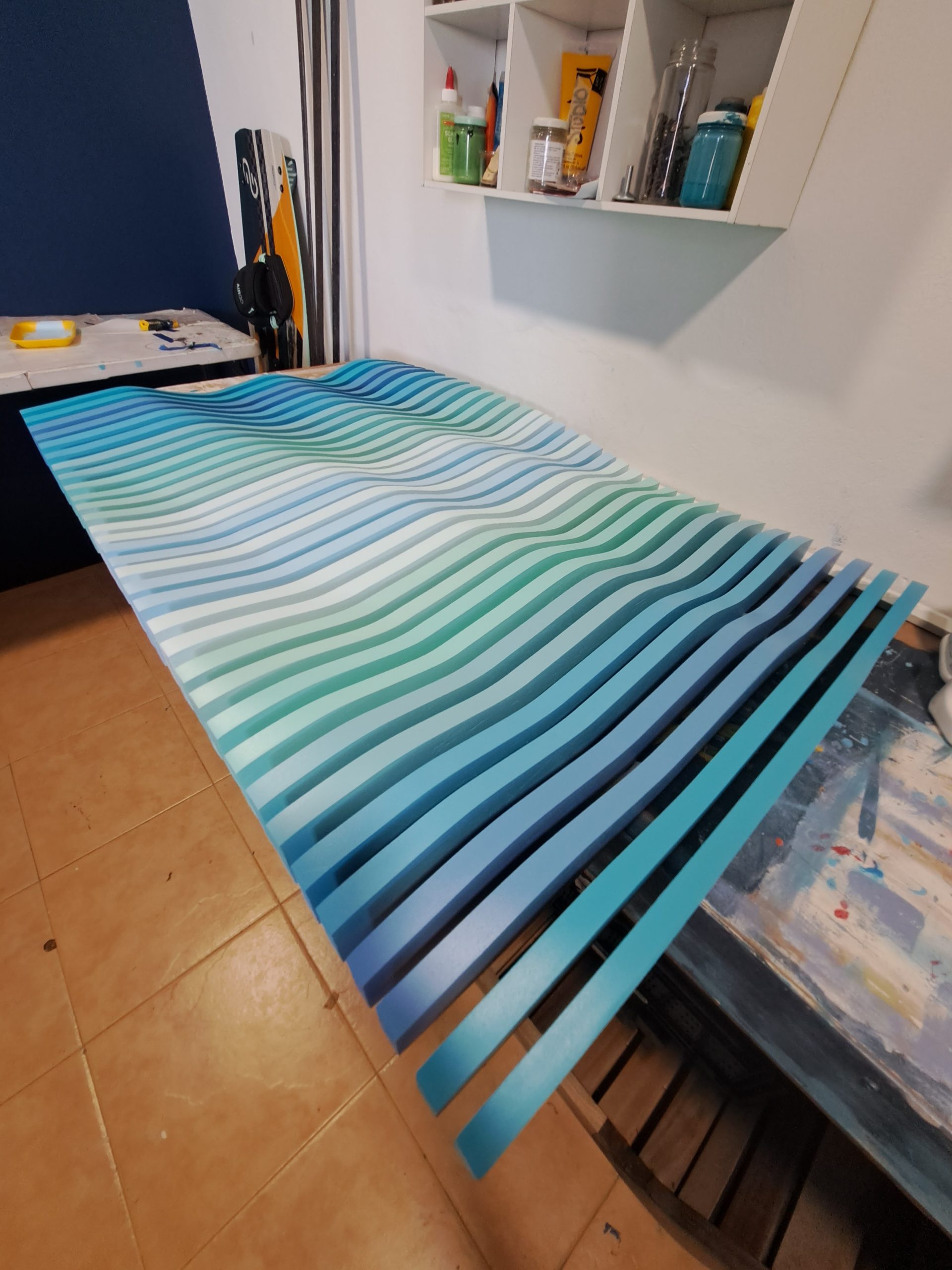 A blue and turquoise wave relief on the workshop table.