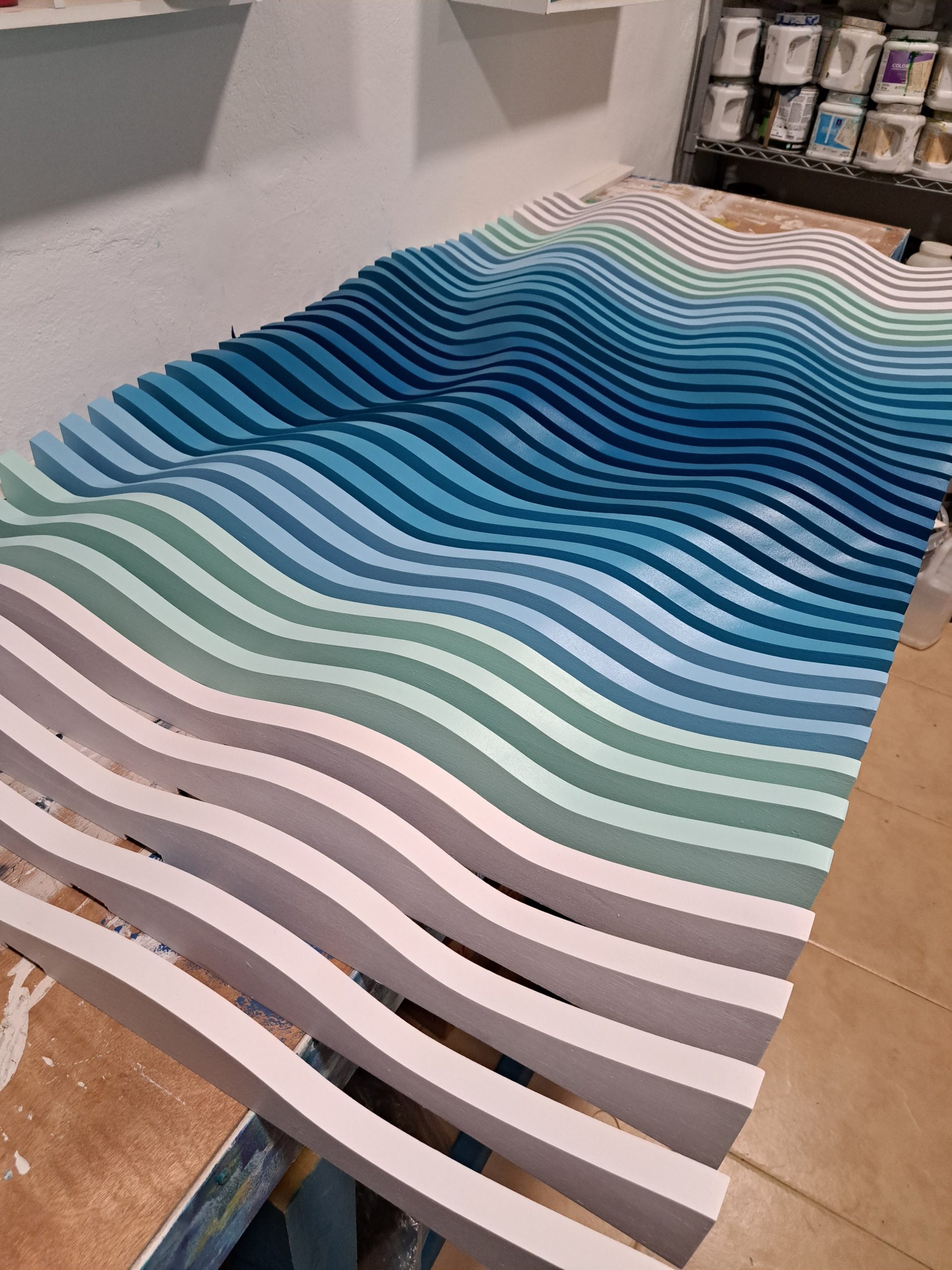 Blue, turquoise and white sculptural wood relief in progress on Juan’s workshop table.